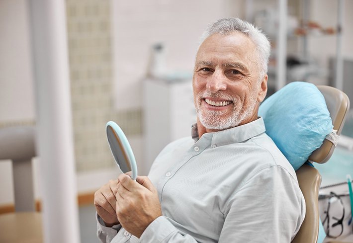 A smiling elderly man sitting in a dentist’s chair