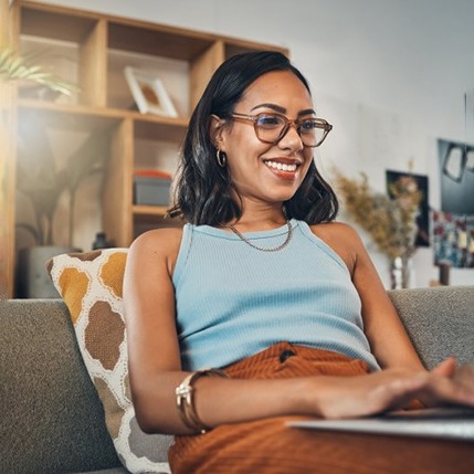 a woman smiling while typing on her laptop