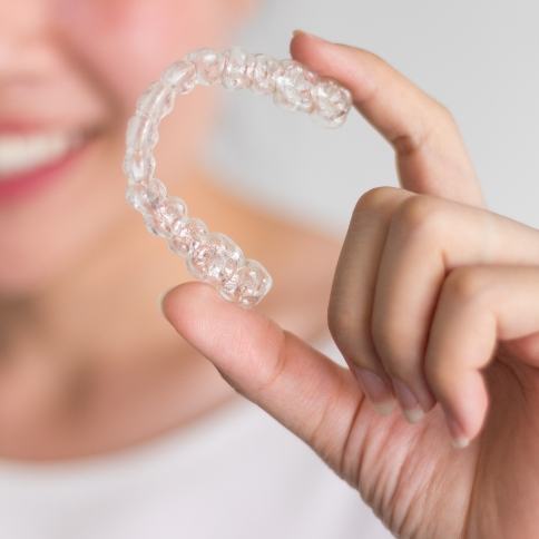 Dental patient holding an Invisalign clear aligner tray