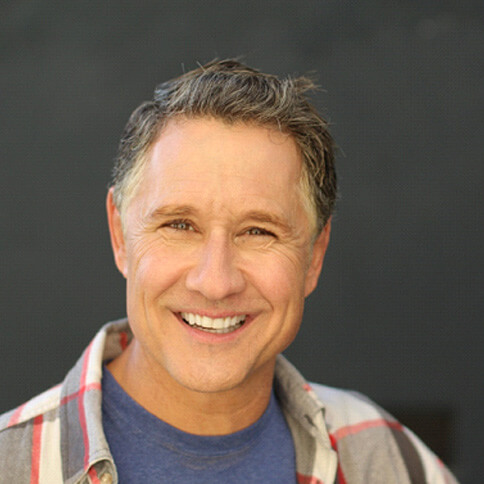 Man smiling in front of a chalkboard