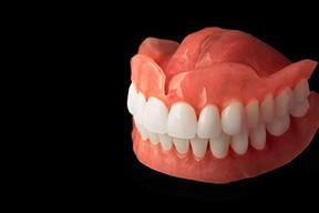 Full upper and lower dentures against dark background