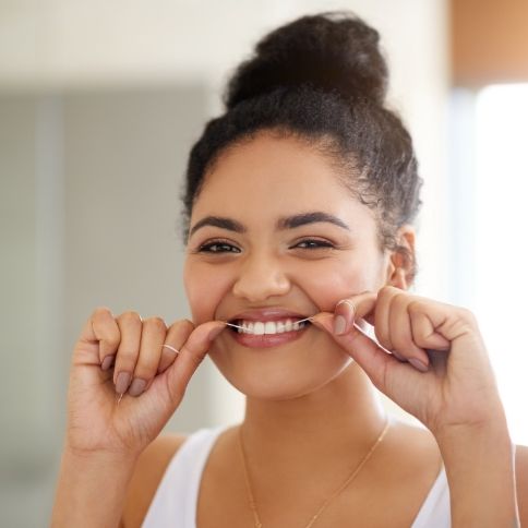 Woman flossing to prevent dental emergencies
