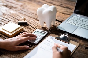 Patient calculating cost of treatment on desk with computer