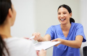 Dental assistant smiling while handing patient form