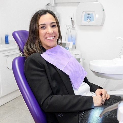 Female patient sitting in dental chair and smiling