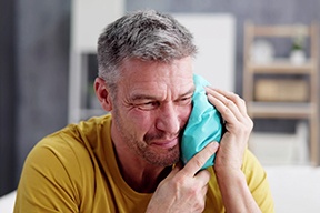 Man with a cold compress on his cheek