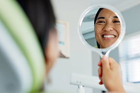 Woman smiling at reflection in dentist office