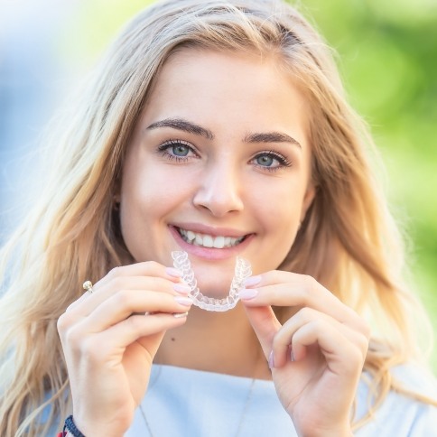 Smiling woman placing Invisalign tray
