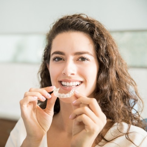 Smiling woman placing an Invisalign tray