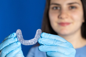 A dentist holding a mouthguard with gloved hands