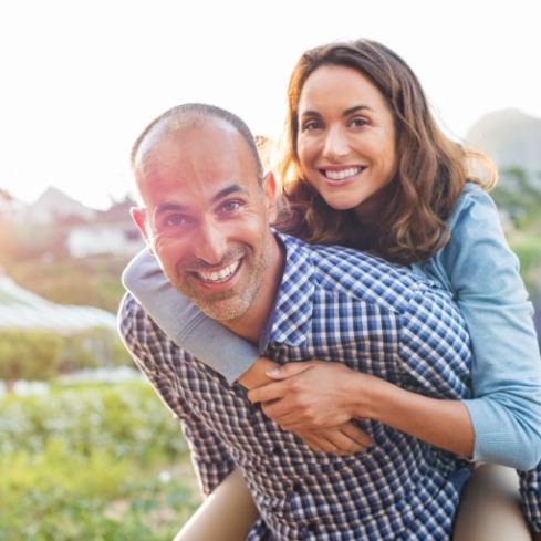 Man and woman smiling after replacing missing teeth