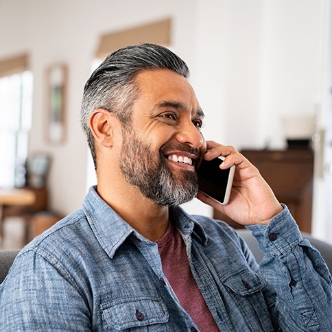 Man smiling while talking on phone at home