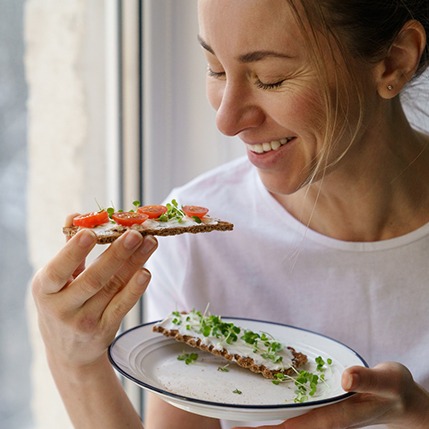 Smiling woman eating healthy snack at home