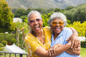Two women smiling and hugging each other outdoors 