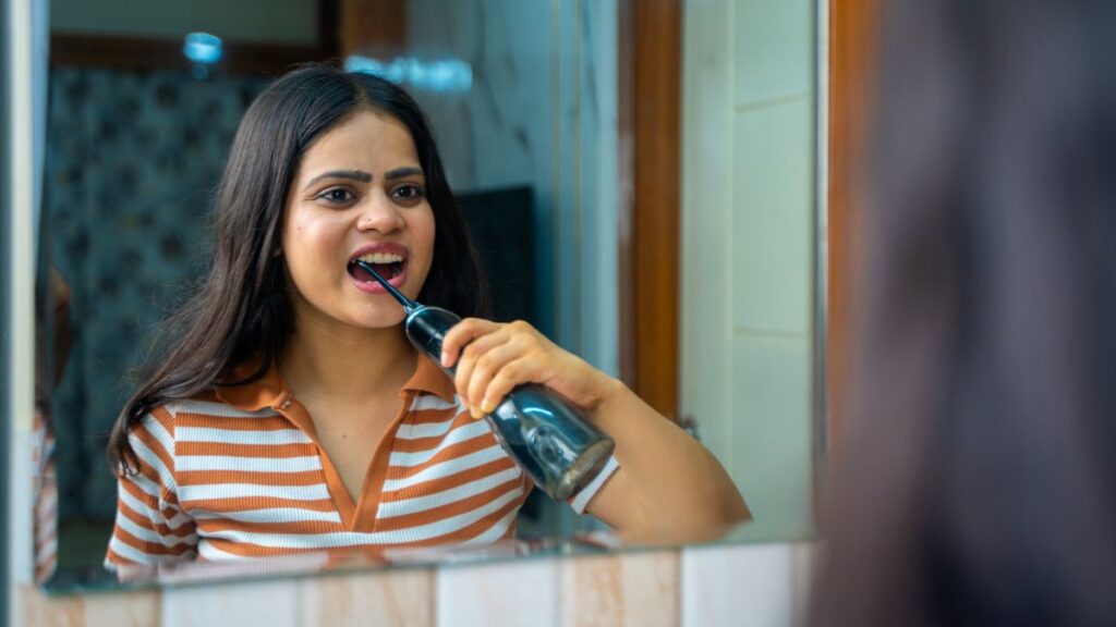 A woman flossing her teeth with a water irrigator